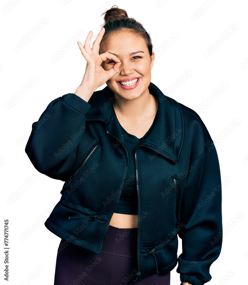 Young hispanic girl wearing sportswear doing ok gesture with hand smiling, eye looking through fingers with happy face. Young hispanic girl wearing sportswear doing ok gesture with hand smiling, eye looking through fingers with happy face.