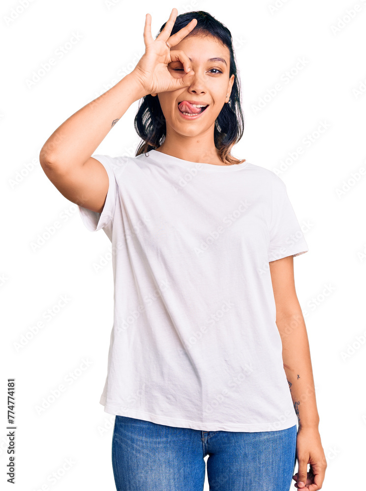 Fototapeta premium Young woman wearing casual clothes doing ok gesture like binoculars sticking tongue out, eyes looking through fingers. crazy expression.