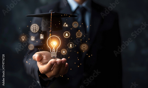 A businessman holds a light bulb with a graduation hat and glowing icons representing education, knowledge sharing, or online learning on a black background, in the style of a training course