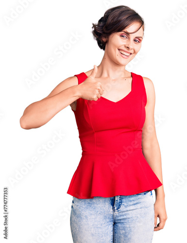 Beautiful young woman with short hair wearing casual style with sleeveless shirt doing happy thumbs up gesture with hand. approving expression looking at the camera showing success.