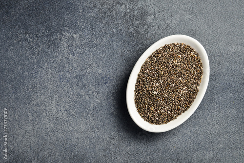 Close up of chia seeds in a ceramic bowl. Superfood On a dark concrete background.