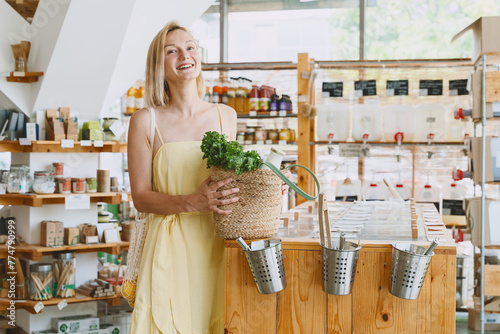 Smiling woman buying organic food and eco products in sustainable plastic free store. Happy female customer shopping at local grocery shop.