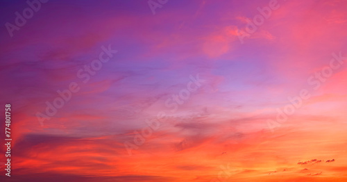 Sunset sky background in the evening with colorful orange, pink, red, yellow sunlight and dramatic sunrise clouds on beautiful amazing twilight horizon sky  © Prapat