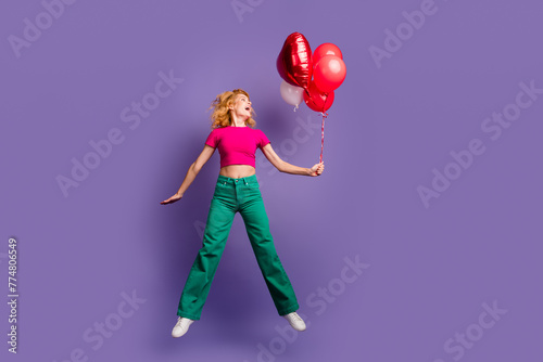Photo of cheerful glad nice lovely woman wear trendy pink clothes look empty space helium balloons isolated on purple color background
