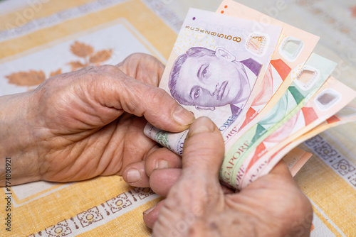 Hands of an elderly woman hold several Singapore dollars in their hands, Economic concept, Home budgets of pensioners in Singapore, rising cost of living and expenses
