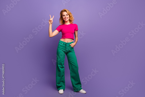 Photo of lovely adorable woman dressed trendy bright clothes hand showing v-sign isolated on purple color background © deagreez
