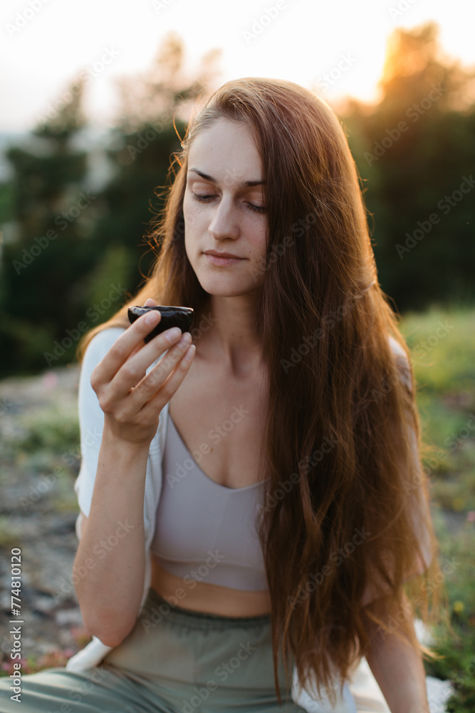 A young beautiful woman performs a Chinese tea ceremony in the mountains at sunset. A young beautiful woman performs a Chinese tea ceremony in the mountains at sunset.