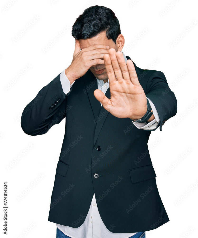 Handsome hispanic man wearing business clothes covering eyes with hands and doing stop gesture with sad and fear expression. embarrassed and negative concept. Handsome hispanic man wearing business clothes covering eyes with hands and doing stop gesture with sad and fear expression. embarrassed and negative concept.