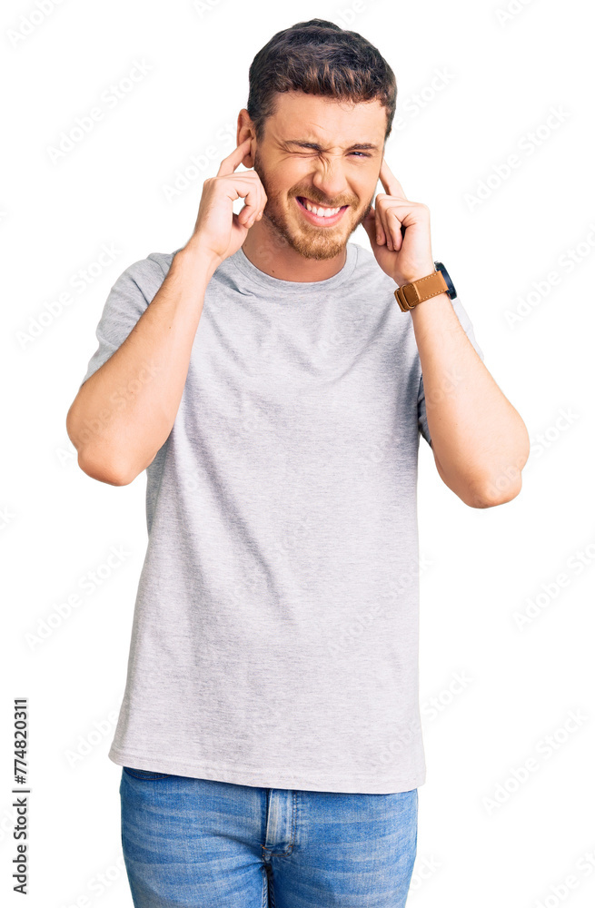 Handsome young man with bear wearing casual tshirt covering ears with fingers with annoyed expression for the noise of loud music. deaf concept. Handsome young man with bear wearing casual tshirt covering ears with fingers with annoyed expression for the noise of loud music. deaf concept.