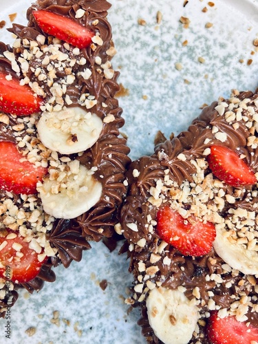 Top view of chocolate croissant with strawberries and banana slices.                                                                                                                