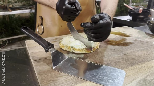 Chef's hands cutting pizza with large knife. Food for gourmets.