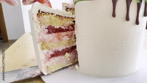 cake with many layers of cream with berry decorate with white mastic. Cut piece.  Side view. Cake on holiday.