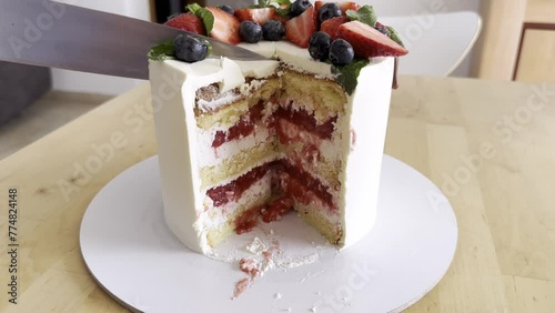 White cake with strawberry filling and decorate by strawberry and blueberry close up. Big beautiful cake for wedding and birthday. Care cut and it is seen all teasty layers of cream, biscuit and jem