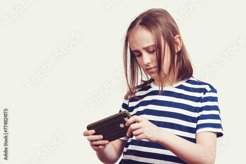 Excited sad boy playing games on mobile phone. Student with mobile phone. Unhappy kid with gadget.
