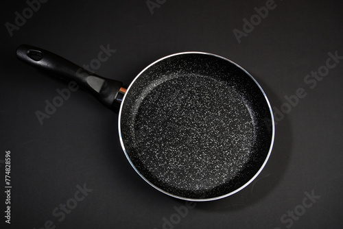Metal frying pan: Ceramic coating with non-stick coating: Kitchen utensils; On a black background: Cooking for chefs in the kitchen.A place for the text..