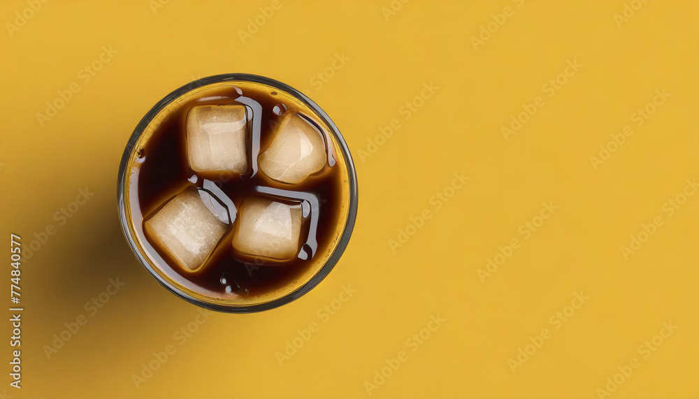 Glass of ice coffee on yellow background, flat lay with copy space. Refreshing drink.
