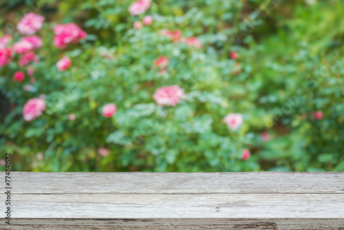 Empty wood table top with blur rose garden background for product display