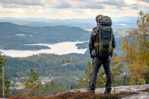 Man with a backpack standing on the summit of a mountain enjoying the achievement of reaching the peak after a challenging hike