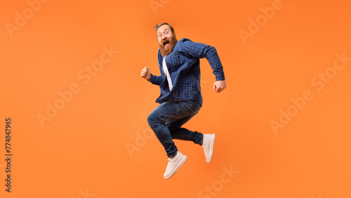 Joyful man with beard jumps and shouting in excitement, studio © Prostock-studio