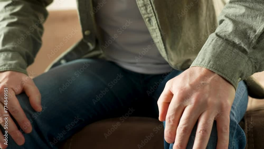 A man sit on sofa suffer from injured knee, close-up. A man sit on sofa suffer from injured knee, close-up.