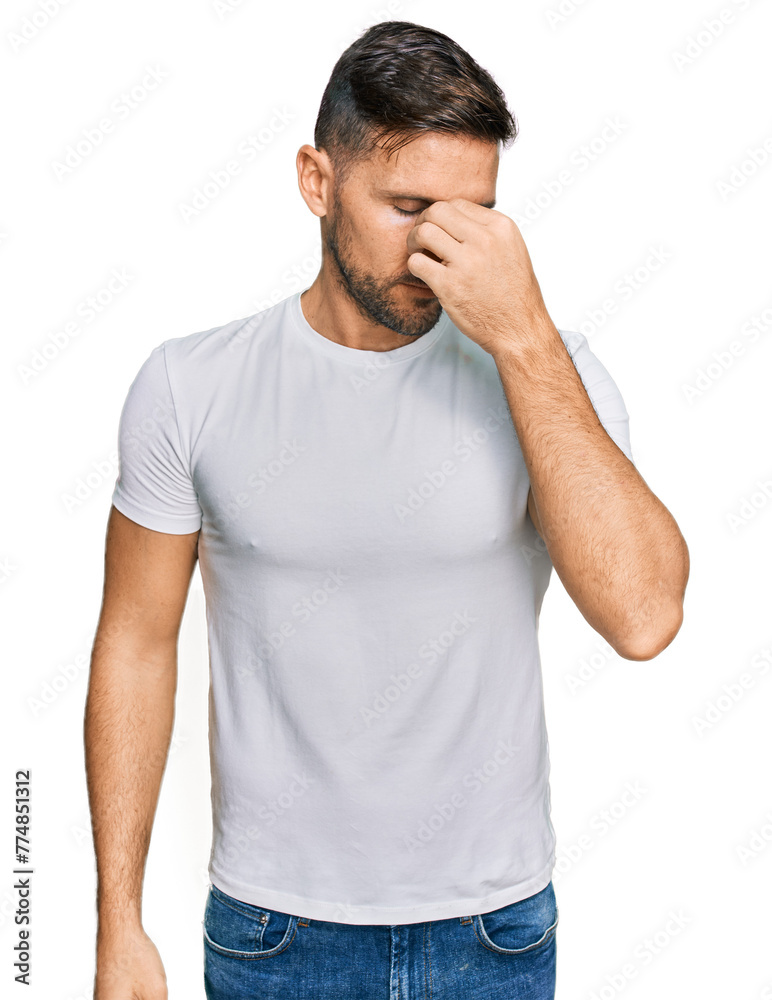 Handsome man with beard wearing casual white t shirt tired rubbing nose and eyes feeling fatigue and headache. stress and frustration concept. Handsome man with beard wearing casual white t shirt tired rubbing nose and eyes feeling fatigue and headache. stress and frustration concept.