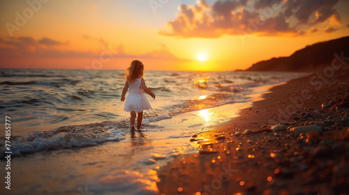 A happy child in light summer clothes walks along the beach at sunset © Irina