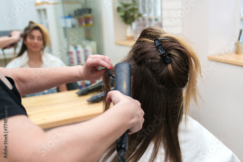 Close-up of hair being straightened at a salon.