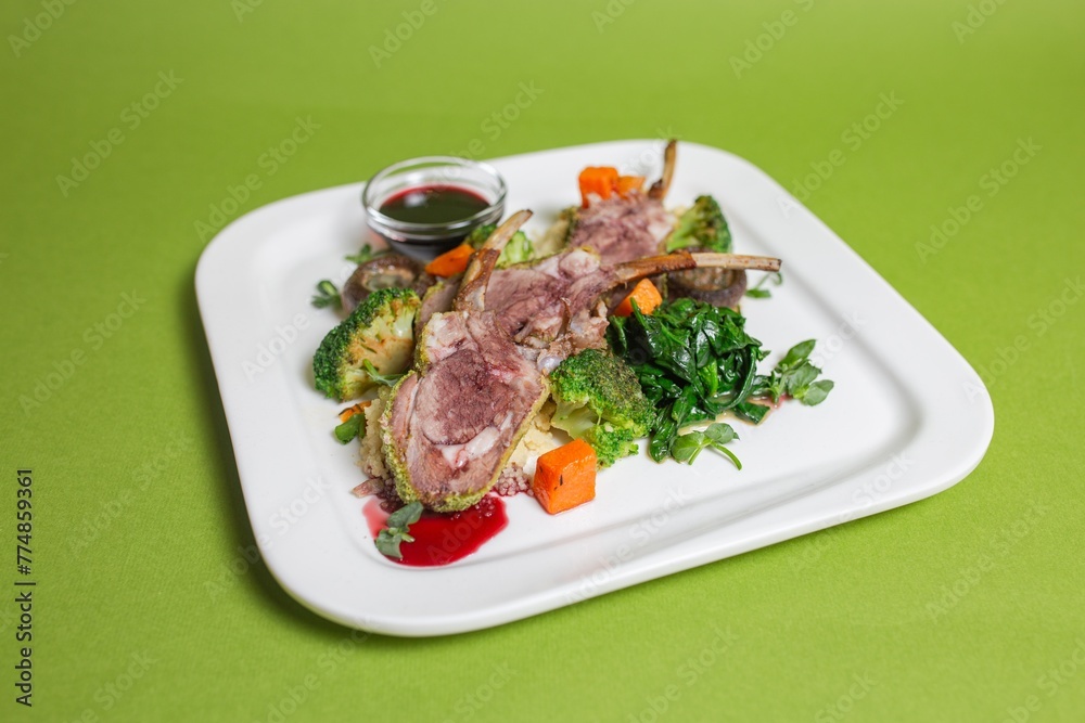 delicious ribs with vegetables and mushrooms on a white plate on a green background delicious ribs with vegetables and mushrooms on a white plate on a green background