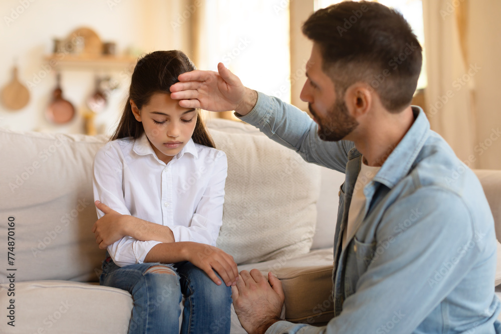 Father checking his daughter's forehead for fever Father checking his daughter's forehead for fever