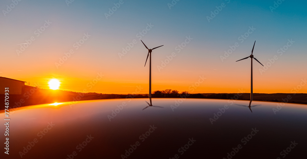 Sunset with wind turbine silhouettes and reflections on a car roof near Kugl, Simbach bei Landau, Dingolfing-Landau, Bavaria, Germany Sunset with wind turbine silhouettes and reflections on a car roof near Kugl, Simbach bei Landau, Dingolfing-Landau, Bavaria, Germany