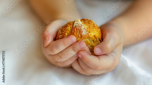 Close-up of a child's hands clasping a small, stale piece of bread, a stark representation of hunger on a white backdrop.