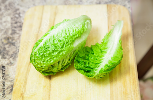 Green romaine lettuce. Baby cos lettuce salad on wooden board  kitchen table.Top view
