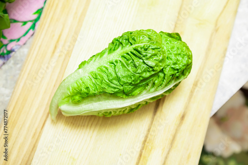 Green romaine lettuce. Baby cos lettuce salad on wooden board  kitchen table.Top view
