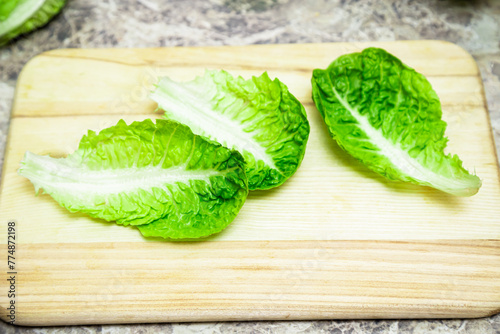 Healthy green romaine lettuce. Baby cos lettuce salad on wooden board  kitchen table.Top view
