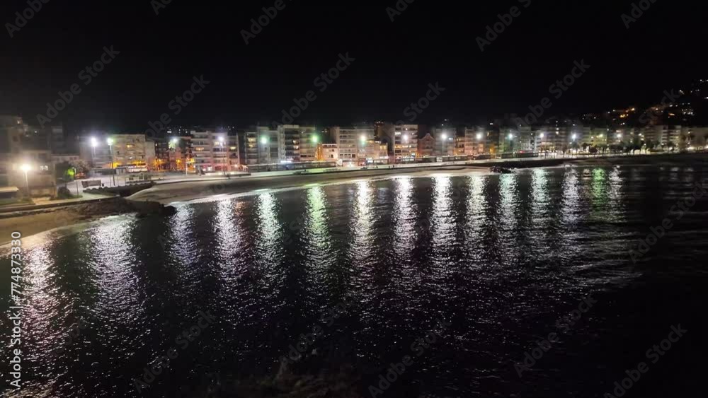 View of the small Spanish town Blanes on the coastline with calm sea at night, 4K View of the small Spanish town Blanes on the coastline with calm sea at night, 4K