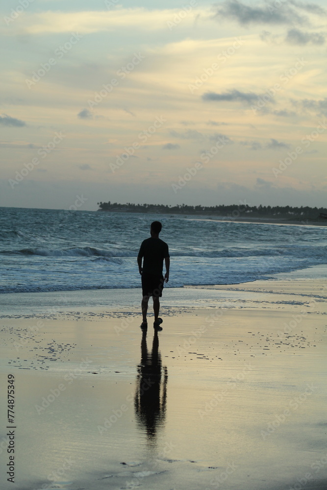 Naklejka premium silhueta de homem não identificado caminhando na Praia da lagoa do Pau (alagoas) ao amanhecer