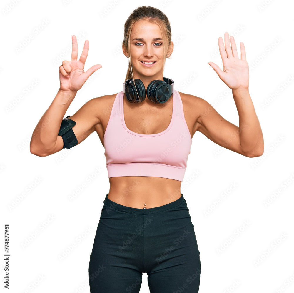 Young blonde woman wearing gym clothes and using headphones showing and pointing up with fingers number eight while smiling confident and happy. Young blonde woman wearing gym clothes and using headphones showing and pointing up with fingers number eight while smiling confident and happy.