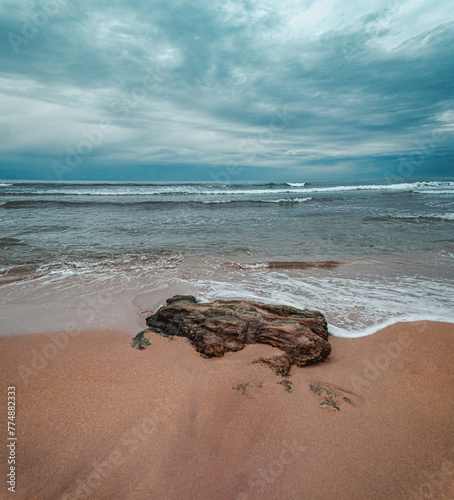 Foamy edges of waves caress the beach in soft grey light