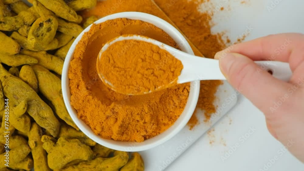 Chef showing turmeric powder shaking it off with spoon, top view, slow motion