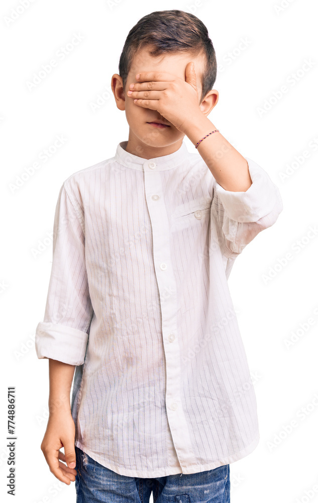 Cute blond kid wearing elegant shirt covering eyes with hand, looking serious and sad. sightless, hiding and rejection concept Cute blond kid wearing elegant shirt covering eyes with hand, looking serious and sad. sightless, hiding and rejection concept