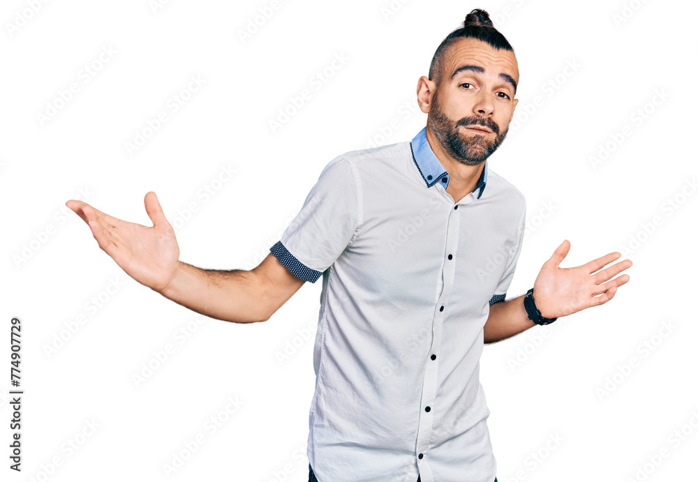 Hispanic man with ponytail wearing casual white shirt clueless and confused expression with arms and hands raised. doubt concept. Hispanic man with ponytail wearing casual white shirt clueless and confused expression with arms and hands raised. doubt concept.