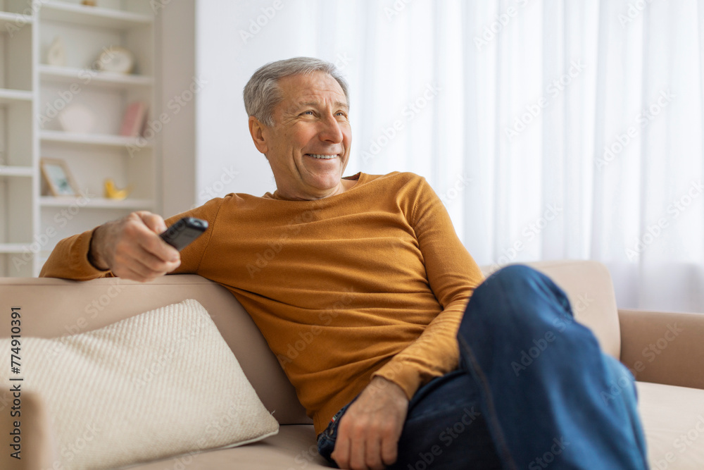 Senior man relaxing on sofa with remote control Senior man relaxing on sofa with remote control