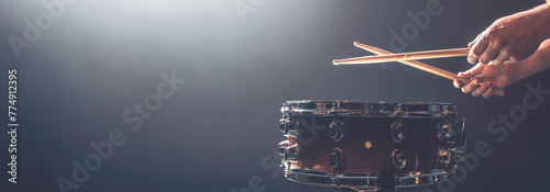 A man plays a snare drum on a dark background, copy space.