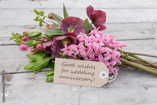 Bouquet with pink hyacinths, Christmas roses and card with English text: Good wishes for wedding anniversary
