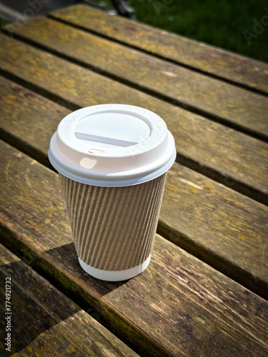 Takeaway coffee cup on a wooden outside table