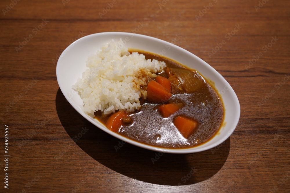 Japanese curry with rice in a white plate on a wooden table Japanese curry with rice in a white plate on a wooden table