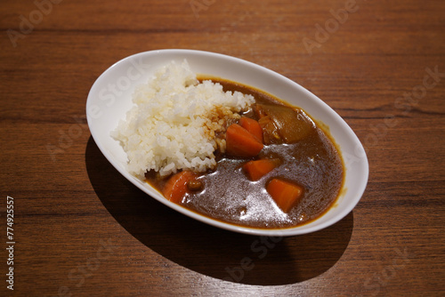 Japanese curry with rice in a white plate on a wooden table © hyungmin