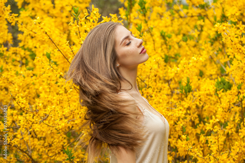 Spring fashion model with long brown hair and natural makeup against floral background outdoor Spring fashion model with long brown hair and natural makeup against floral background outdoor