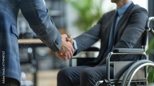 Inclusion: Job interview - Close up of two business people shaking hands, one in wheelchair. Business meeting concept successful interview or meeting.