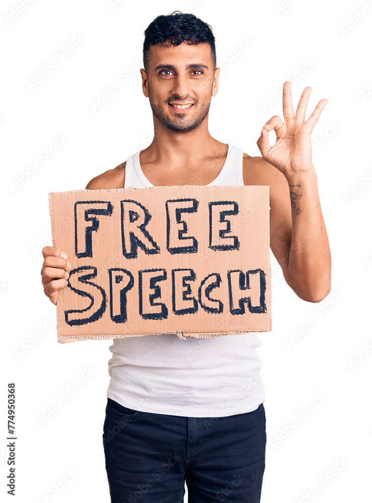 Young hispanic man holding free speech banner doing ok sign with fingers, smiling friendly gesturing excellent symbol Young hispanic man holding free speech banner doing ok sign with fingers, smiling friendly gesturing excellent symbol